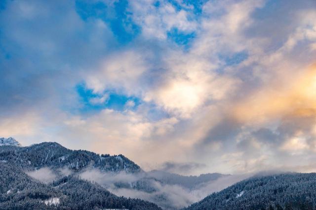 The setting sun cutting through the clouds colours the sky yellow behind the mountain peaks outside the village of Niederdorf (Villabassa), between the Olympic venues in Cortina and Antholz, northern Italy prior to the Milano Cortina 2026 Olympic Games, on January 29, 2026. (Photo by Odd ANDERSEN / AFP)