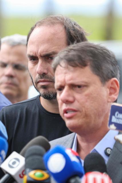 Tarcisio de Freitas (C), governor of the state of Sao Paulo, speaks to reporters accompanied by Carlos Bolsonaro, son of former Brazilian President Jair Bolsonaro, after visiting Jair Bolsonaro, imprisoned at the Papuda penitentiary complex in Brasilia, on January 29, 2026. (Photo by Sergio Lima / AFP)