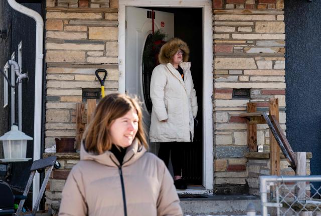 This January 28, 2026, photo shows residents outside of a home looking on as as other neighborhood residents surround two vehicles and blow whistles at nearby federal immigration agents in Minneapolis, Minnesota. The Trump administration said on January 28 that two immigration agents involved in the fatal shooting of a civilian in Minneapolis had been placed on leave, as the president slammed the citys mayor despite a promise to de-escalate the situation. The officers have been on leave -- a move US officials said was "standard protocol" -- since Saturday, when Alex Pretti was shot multiple times after being forced to the ground by camouflaged officers in a scuffle captured on video. (Photo by ROBERTO SCHMIDT / AFP)