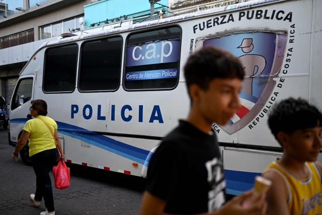 People walk past a police vehicle in downtown San Jose on January 29, 2026. Right-wing politician Laura Fernandez appears set to win Costa Rica's presidential election in the first round, according to two opinion polls published on January 21. (Photo by Marvin RECINOS / AFP)