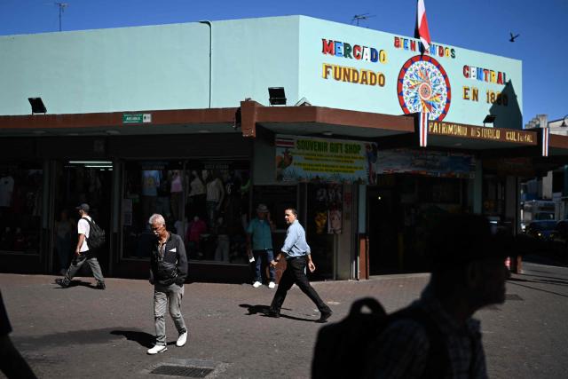Men walk past the entrance of the Central Market in downtown San Jose on January 29, 2026. Right-wing politician Laura Fernandez appears set to win Costa Rica's presidential election in the first round, according to two opinion polls published on January 21. (Photo by Marvin RECINOS / AFP)