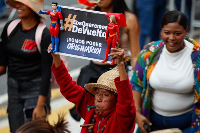 A woman holds toys of the caped superhero ‘Super-Bigote’ (Super-Mustache) and ‘Cilita,’ during a march called by the United Socialist Party of Venezuela (PSUV) in support of the Hydrocarbons Law and demanding the release of ousted President Nicolas Maduro, in Caracas on January 29, 2026. (Photo by Pedro MATTEY / AFP)