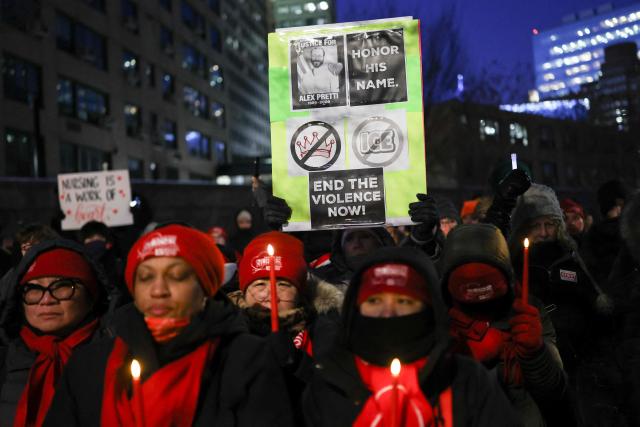 People hold signs and candles during a vigil for Alex Pretti, a 37-year-old nurse who was fatally shot by immigration agents in Minneapolis, at the Veterans Affairs NY Harbor Healthcare System Manhattan Campus in New York, on January 29, 2026. US President Donald Trump said on January 27 that he would "de-escalate a little bit" in Minneapolis after the fatal shootings of two civilians fueled a storm of criticism over his signature immigration crackdown. (Photo by ANGELA WEISS / AFP)