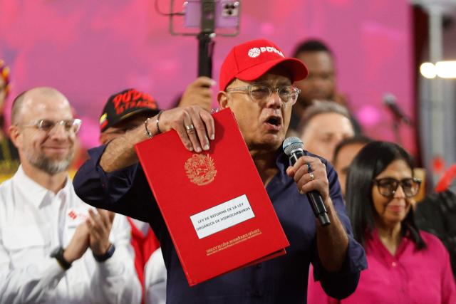 The President of Venezuela’s National Assembly, Jorge Rodriguez, holds a copy of the Reform of the Organic Law on Hydrocarbons outside the Miraflores Presidential Palace in Caracas on January 29, 2026. Venezuela adopted a reform opening its nationalized oil sector to private investment on January 29 as it moves to appease the United States following the toppling of leader Nicolas Maduro. (Photo by Pedro MATTEY / AFP)