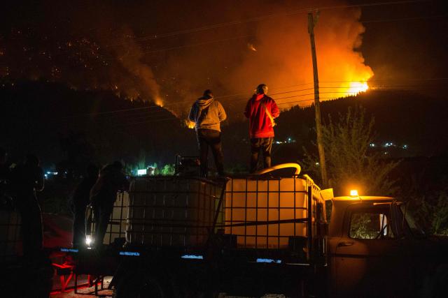 (FILES) People wait on top of a water truck as a forest fire burns at Mount Pirque at El Hoyo, in the Patagonian region of Chubut province, Argentina on January 7, 2026. The government of Argentine President Javier Milei announced on January 29, 2026, that it will declare a "fire emergency" in four provinces in Patagonia, where several fires have consumed tens of thousands of hectares since the beginning of the southern hemisphere summer. (Photo by Martin LEVICOY / AFP)