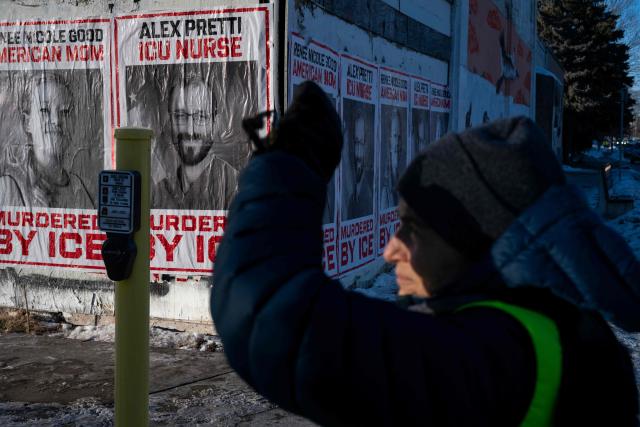 A resident of Minneapolis mans a corner to keep an eye out for US Immigration and Customs Enforcement (ICE) agents near a school where some students were recently arrested in Minneapolis, Minnesota, on January 29, 2026. US President Donald Trump's border chief Tom Homan said on January 29 that some federal agents could be withdrawn from Minneapolis, the northern US city that has become the flashpoint for the president's immigration crackdown. The Trump administration, facing a public backlash over the shooting deaths of two Americans by federal agents in Minneapolis, also eased immigration operations in the northeastern state of Maine. (Photo by ROBERTO SCHMIDT / AFP)