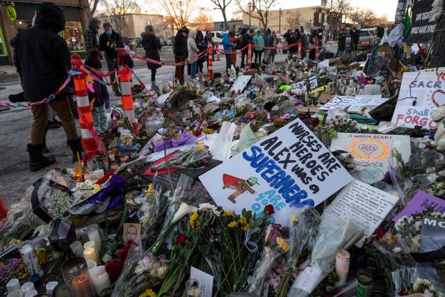 People visit the makeshift memorial for Alex Pretti set up in the area where he was recently shot and killed by federal immigration agents in Minneapolis, Minnesota, on January 29, 2026. US President Donald Trump's border chief Tom Homan said on January 29 that some federal agents could be withdrawn from Minneapolis, the northern US city that has become the flashpoint for the president's immigration crackdown. The Trump administration, facing a public backlash over the shooting deaths of two Americans by federal agents in Minneapolis, also eased immigration operations in the northeastern state of Maine. (Photo by ROBERTO SCHMIDT / AFP)