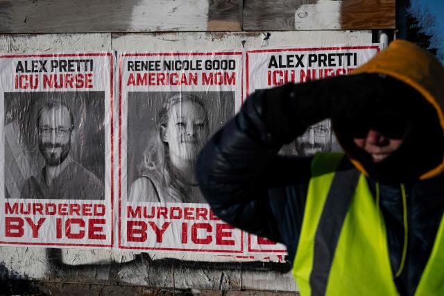 Backdropped by posters with images of Renne Good and Alex Pretti, the two US citizens recently shot and killed by federal immigration officers, a resident of Minneapolis mans a corner to keep an eye out for ICE agents near a school where some students were recently arrested in Minneapolis, Minnesota, on January 29, 2026. US President Donald Trump's border chief Tom Homan said on January 29 that some federal agents could be withdrawn from Minneapolis, the northern US city that has become the flashpoint for the president's immigration crackdown. The Trump administration, facing a public backlash over the shooting deaths of two Americans by federal agents in Minneapolis, also eased immigration operations in the northeastern state of Maine. (Photo by ROBERTO SCHMIDT / AFP)