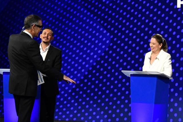Costa Rica's presidential candidates Ariel Robles (C) and Claudia Dobles (R) talk with journalist Ignacio Santos (L) before the final presidential debate at Canal 7 television studios in San Jose on January 29, 2026. Costa Rica will hold a presidential election on February 1, 2026. (Photo by Ezequiel BECERRA / AFP)