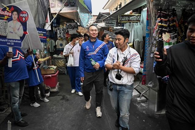 Former snooker player Wattana Pu-Ob-Orm (C), known professionally as James Wattana, campaigns for the United Thai Nation Party with fellow MP candidate Kanyavee Jarusamphankanok (R) ahead of the general election in Bangkok on January 29, 2026. (Photo by Lillian SUWANRUMPHA / AFP)