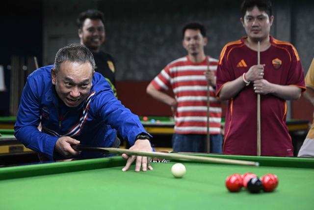 Former snooker player Wattana Pu-Ob-Orm, known professionally as James Wattana, plays at a snooker hall as he campaigns for the United Thai Nation Party ahead of the general election in Bangkok on January 29, 2026. (Photo by Lillian SUWANRUMPHA / AFP)