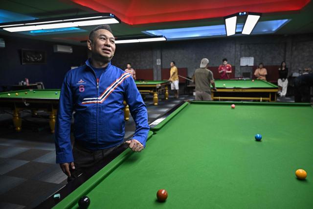 Former snooker player Wattana Pu-Ob-Orm (L), known professionally as James Wattana, visits a snooker hall as he campaigns for the United Thai Nation Party ahead of the general election in Bangkok on January 29, 2026. (Photo by Lillian SUWANRUMPHA / AFP)