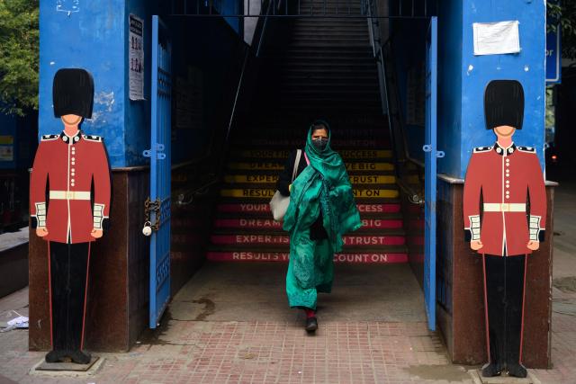 A woman walks past cut-outs of the iconic 'London Guards' outside a metro station in New Delhi on January 30, 2026. (Photo by Manan VATSYAYANA / AFP)