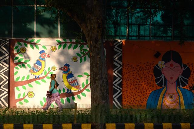 A pedestrian walks past a mural along a street in New Delhi on January 30, 2026. (Photo by Manan VATSYAYANA / AFP)