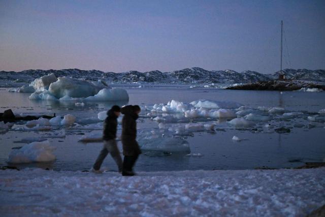 Two persons walk past ice blocks floating on the sea in the harbour of Nuuk, Greenland on January 29, 2026. (Photo by Ina FASSBENDER / AFP)