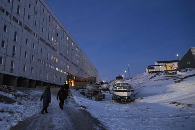 People walk past boats parked in a residential area of Nuuk, Greenland on January 29, 2026. (Photo by Ina FASSBENDER / AFP)