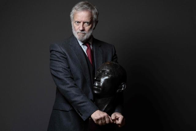 French actor Francis Huster poses with a bust of the French actor Louis Jouvet during a photo session at the Theatre Antoine in Paris on January 28, 2026. He hopes to keep performing "for the next ten years": at 78, Francis Huster is returning to the stage as the therapist in the play "En Therapie", a theatrical adaptation of the eponymous series, delighted to refresh his craft alongside the younger generation. (Photo by Joel Saget / AFP)