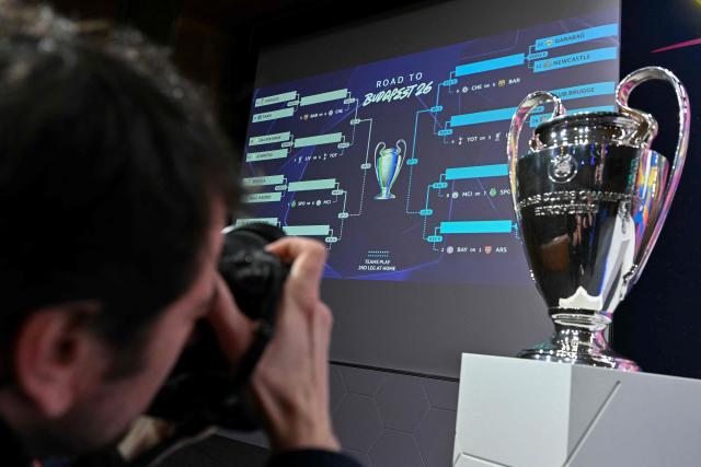 A photograph takes images of the UEFA Champions League Cup displayed next to the results appearing on a giant screen after the 2025-2026 UEFA Europa League knockout phase play-off draw at the House of European Football in Nyon on January 30, 2026. The draw involves the teams finishing in ninth to 24th place in the league phase – the top eight sides in the league phase qualifying automatically for the round of 16. (Photo by Harold CUNNINGHAM / AFP)