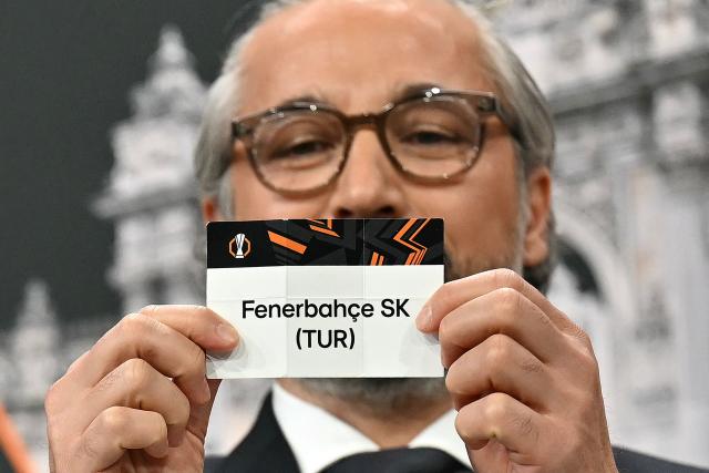 Turkish former football player and UEFA Europa League ambassador Ilhan Mansiz holds up the slip of Fenerbahзe (TUR) during the 2025-2026 UEFA Europa League knockout phase play-off draw at the House of European Football in Nyon on January 30, 2026. The draw involves the teams finishing in ninth to 24th place in the league phase – the top eight sides in the league phase qualifying automatically for the round of 16. (Photo by Harold CUNNINGHAM / AFP)