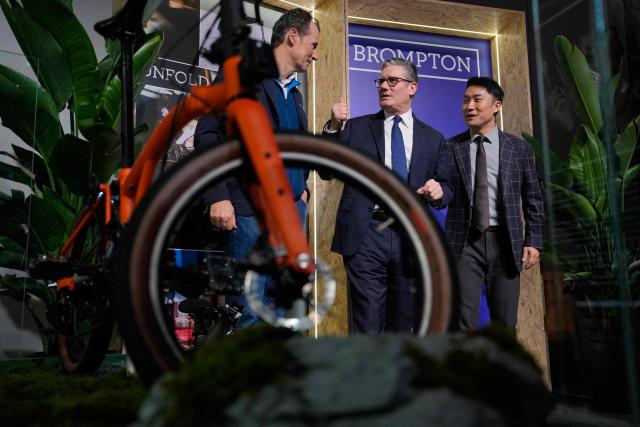 Britain's Prime Minister Keir Starmer looks at a Brompton folding bike at a Brompton display stand at a House of UK reception in Shanghai on January 30, 2026. (Photo by Kin Cheung / POOL / AFP)