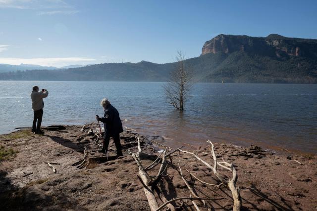 Persons stand on the shore of the reservoir of Sau in Vilanova de Sau in Catalonia amid high water-level, on January 30, 2026 . This long-Term project shows photos of the same places taken every month over a very long period. (Photo by Josep LAGO / AFP)