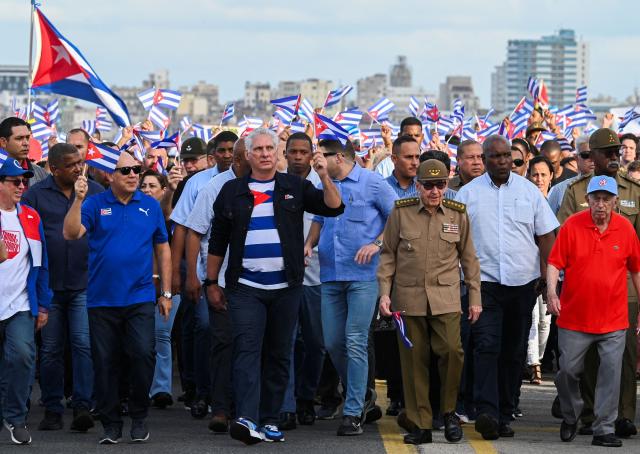 (FILES) Cuba's President Miguel Diaz-Canel (C) and former Cuban President Raul Castro (2nd R) walk past the US embassy as they march along Havana's promenade on December 20, 2024, during a demonstration against the blockade and Cuba's remaining on the list of countries that sponsor terrorism. Cuban President Miguel Diaz-Canel on January 30, 2026, denounced US President Donald Trump’s attempt to “asphyxiate” the communist island’s economy under a “false pretext.” (Photo by YAMIL LAGE / AFP)