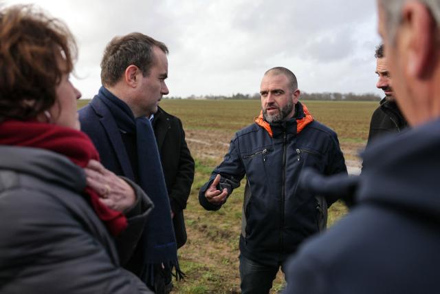 France's Prime Minister Sebastien Lecornu (L) speaks with a farmer as he tours an almond orchard during a visit to promote local and diversified agriculture, in Baigneaux, central France, on January 30, 2026. The prime minister is visiting the Eure-et-Loire department to launch the "contracts for the future" demanded by the Jeunes Agriculteurs (Young Farmers) union, aimed at diversifying production, notably in the face of climate change, and to present the Governments efforts to increase the share of local food in public procurement. (Photo by Thomas SAMSON / AFP)