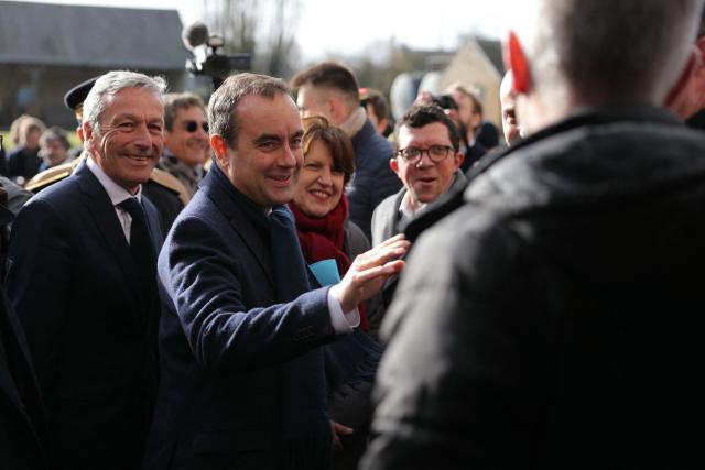 Les Democrates' MP Philippe Vigier (L), France's Prime Minister Sebastien Lecornu (2nd L) and France's Agriculture Minister Annie Genevard (3rd L) are welcomed as they arrive to a farm during a visit to promote local and diversified agriculture, in Baigneaux, central France, on January 30, 2026. The prime minister is visiting the Eure-et-Loire department to launch the "contracts for the future" demanded by the Jeunes Agriculteurs (Young Farmers) union, aimed at diversifying production, notably in the face of climate change, and to present the Governments efforts to increase the share of local food in public procurement. (Photo by Thomas SAMSON / AFP)