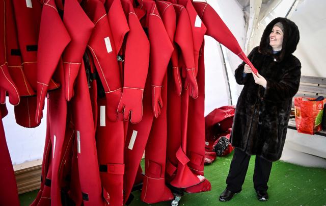 A participant looks at isothermal wetsuits as she gets ready to float among ice floes in a hole on the frozen Moskva river during an ice floating session - the growing relaxation trend, in Moscow on January 30, 2026. (Photo by Alexander NEMENOV / AFP)
