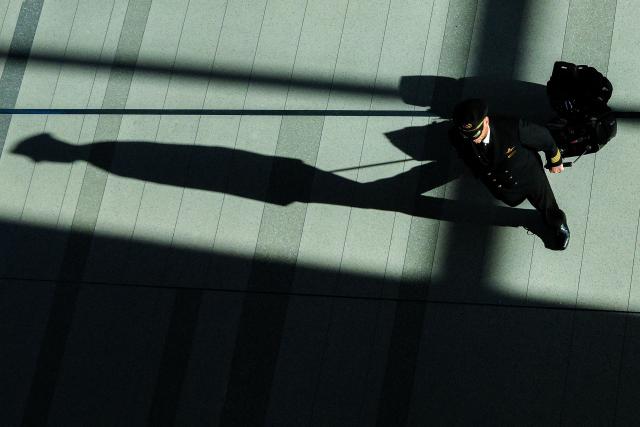 A Delta Airlines flight captain walks in a terminal at the LaGuardia airport in New York City on January 30, 2026. (Photo by CHARLY TRIBALLEAU / AFP)