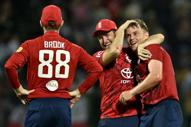 England's Liam Dawson (C) congratulates England's Sam Curran (R) after taking the hat trick wicket of Sri Lanka's Matheesha Pathirana (not pictured) during the first Twenty20 international cricket match between Sri Lanka and England at the Pallekele International Cricket Stadium in Kandy on January 30, 2026. (Photo by Ishara S. KODIKARA / AFP)