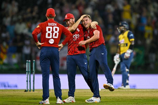 England's Liam Dawson (C) congratulates England's Sam Curran (R) after taking the hat trick wicket of Sri Lanka's Matheesha Pathirana (not pictured) during the first Twenty20 international cricket match between Sri Lanka and England at the Pallekele International Cricket Stadium in Kandy on January 30, 2026. (Photo by Ishara S. KODIKARA / AFP)