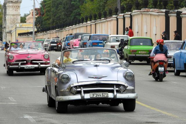 Tourists traveling in vintage American cars drive past vehicles waiting in line to refuel at a gas station in Havana on January 30, 2026. Cuban President Miguel Diaz-Canel on January 30, 2026, denounced US President Donald Trump’s attempt to “asphyxiate” the communist island’s economy under a “false pretext.” (Photo by ADALBERTO ROQUE / AFP)