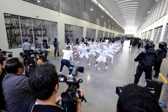 Inmates excercise during a visit by Chile’s president-elect Jose Antonio Kast (out of frame) to the Counter-Terrorism Confinement Centre (CECOT) mega-prison, where hundreds of MS-13 and 18th Street gang members are being held, in Tecoluca, El Salvador, on January 29, 2026. The CECOT, the largest prison in Latin America and emblem of the war against gangs of the government of President Nayib Bukele, celebrates two years since it was inaugurated on February 1. (Photo by Oscar RIVERA / AFP)