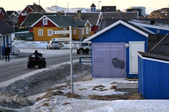 A quad drives past a poster with a musk ox at the city of Sisimiut, Greenland on January 30, 2026. (Photo by Ina FASSBENDER / AFP)