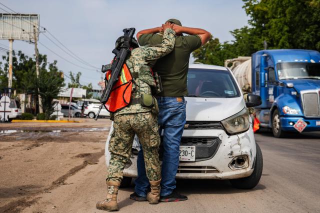 TOPSHOT - A Mexican soldier searches a man at a security checkpoint on a street in Culiacan, Sinaloa state, Mexico on January 30, 2026. Security in the northwestern Mexican state of Sinaloa was reinforced with 1,600 military personnel on January 29, 2026, after two local deputies were shot and ten workers from a Canadian mine were kidnapped. The troops were deployed just as President Claudia Sheinbaum was on the phone with her US counterpart, Donald Trump, to discuss security and trade. (Photo by Jesus VERDUGO / AFP)