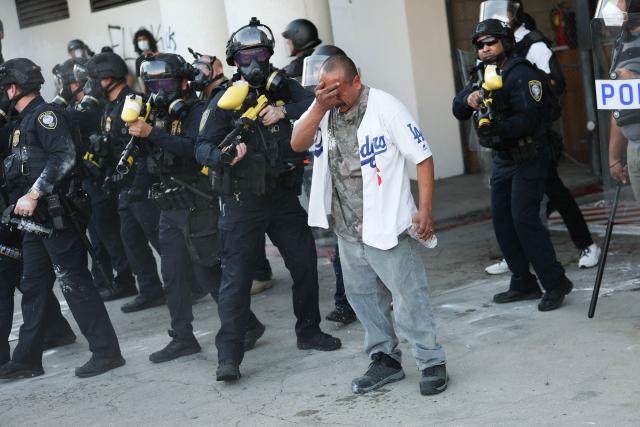 A man reacts after being gassed by police during a "National Shutdown" protest against U.S. Immigration and Customs Enforcement in Los Angeles on January 30, 2026. Donald Trump's border chief said January 29, 2026 that some federal agents could be withdrawn from Minneapolis, the northern US city that has become the flashpoint for the president's immigration crackdown. The Trump administration, facing a public backlash over the shooting deaths of two Americans by federal agents in Minneapolis, also eased immigration operations in the northeastern state of Maine. (Photo by Patrick T. Fallon / AFP)