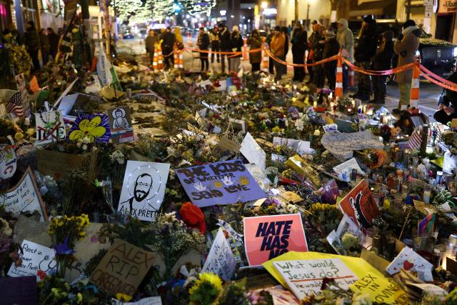 People visit the makeshift memorial for Alex Pretti, set up in the area where he was recently shot and killed by federal immigration agents, in Minneapolis, Minnesota, on January 30, 2026. Donald Trump's border chief said January 29, 2026 that some federal agents could be withdrawn from Minneapolis, the northern US city that has become the flashpoint for the president's immigration crackdown. The Trump administration, facing a public backlash over the shooting deaths of two Americans by federal agents in Minneapolis, also eased immigration operations in the northeastern state of Maine. (Photo by CHARLY TRIBALLEAU / AFP)
