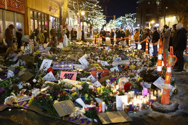 People visit the makeshift memorial for Alex Pretti, set up in the area where he was recently shot and killed by federal immigration agents, in Minneapolis, Minnesota, on January 30, 2026. Donald Trump's border chief said January 29, 2026 that some federal agents could be withdrawn from Minneapolis, the northern US city that has become the flashpoint for the president's immigration crackdown. The Trump administration, facing a public backlash over the shooting deaths of two Americans by federal agents in Minneapolis, also eased immigration operations in the northeastern state of Maine. (Photo by CHARLY TRIBALLEAU / AFP)