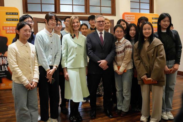 Britain's Prime Minister Keir Starmer (C) and British actor-producer Rosamund Pike (centre L) pose for a photo with Chinese performing arts students at the Design Innovation Institute Shanghai, in Shanghai on January 31, 2026. (Photo by Kin Cheung / POOL / AFP)