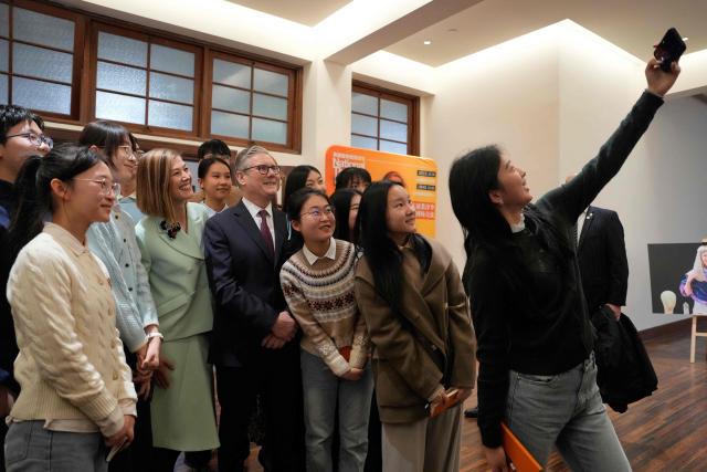 Britain's Prime Minister Keir Starmer (C) and British actor-producer Rosamund Pike (3rd L) pose for a selfie with Chinese performing arts students at the Design Innovation Institute Shanghai, in Shanghai on January 31, 2026. (Photo by Kin Cheung / POOL / AFP)