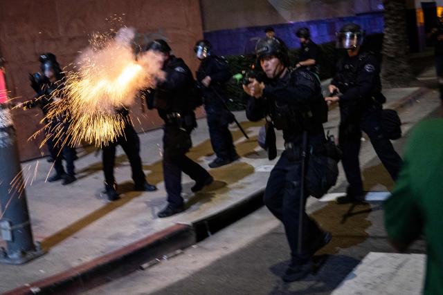 An LAPD officer fires a non-lethal munition while facing protesters during a "National Shutdown" protest against US Immigration and Customs Enforcement in Los Angeles on January 30, 2026. Donald Trump's border chief said January 29, 2026 that some federal agents could be withdrawn from Minneapolis, the northern US city that has become the flashpoint for the president's immigration crackdown. The Trump administration, facing a public backlash over the shooting deaths of two Americans by federal agents in Minneapolis, also eased immigration operations in the northeastern state of Maine. (Photo by ETIENNE LAURENT / AFP)