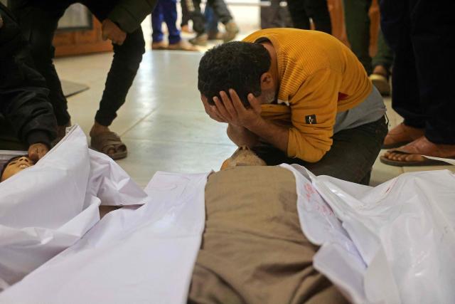 EDITORS NOTE: Graphic content / TOPSHOT - A mourner weeps next to the bodies of Palestinians, who were reportedly killed by an Israeli air strike, in Khan Yunis, southern Gaza Strip on January 31, 2026. Israeli air strikes killed 11 people in the Gaza Strip on January 31, according to the territory's ministry of health, including people sheltering in a tent in the south. (Photo by Bashar Taleb / AFP)