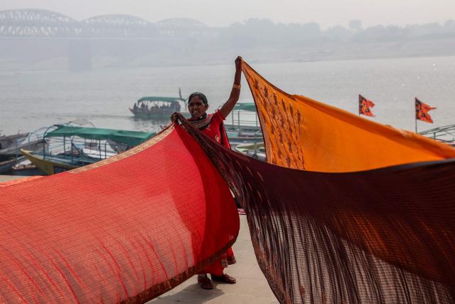 A woman dries sarees after taking a dip in the river Ganges amid smoggy conditions in Varanasi on January 31, 2026. (Photo by Niharika KULKARNI / AFP)