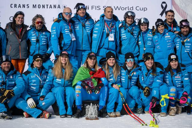 Second-placed Italy's Sofia Goggia (C) celebrates with her team on the podium after competing in the women's super G race part of the FIS Alpine Ski World Cup 2025-2026, in Crans Montana, Switzerland, on January 31, 2026. (Photo by Fabrice COFFRINI / AFP)