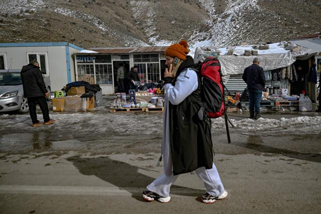 An Iranian woman makes a phone call as she waits for a minibus after arriving in Turkey through the RaziKapiköy border crossing, north-eastern Turkey, on January 31, 2026. Iranian army chief Amir Hatami on Saturday warned the United States and Israel against an attack, saying his country's forces were on high alert following Washington's heavy military deployments in the Gulf. He also insisted the Islamic republic's nuclear expertise could not be eliminated, after Trump said he expected Tehran to seek a deal to avoid US strikes. (Photo by Ozan KOSE / AFP)