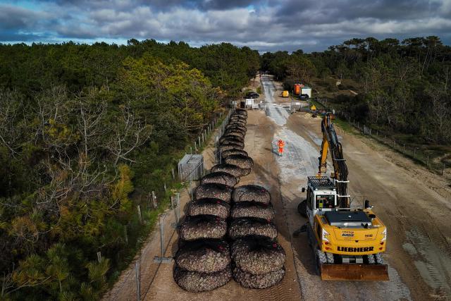 An aerial view shows construction machinery and workers at the Trillou coastal protection site as gabion baskets filled with rocks await transport to the beach during emergency coastal protection works at Allassins beach in Grand-Village-Plage, on the island of Oléron, south-western France, on January 28, 2026. The infiltration basins, which return treated wastewater to the natural environment, are now critically threatened by coastal erosion, with only a narrow strip of degraded dune vegetation separating them from the beach as the shoreline has already receded 25 meters, reaching erosion levels originally forecast for 2030. (Photo by Philippe LOPEZ / AFP)