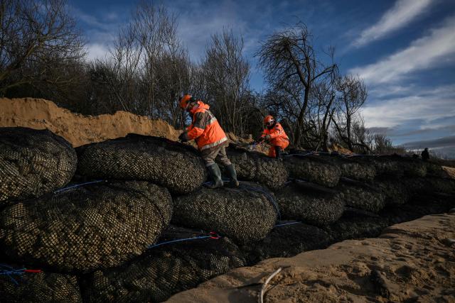 Workers secure rock-filled gabion baskets during emergency coastal protection works at Allassins beach in Grand-Village-Plage, on the island of Oléron, south-western France, on January 28, 2026. The infiltration basins, which return treated wastewater to the natural environment, are now critically threatened by coastal erosion, with only a narrow strip of degraded dune vegetation separating them from the beach as the shoreline has already receded 25 meters, reaching erosion levels originally forecast for 2030. (Photo by Philippe LOPEZ / AFP)