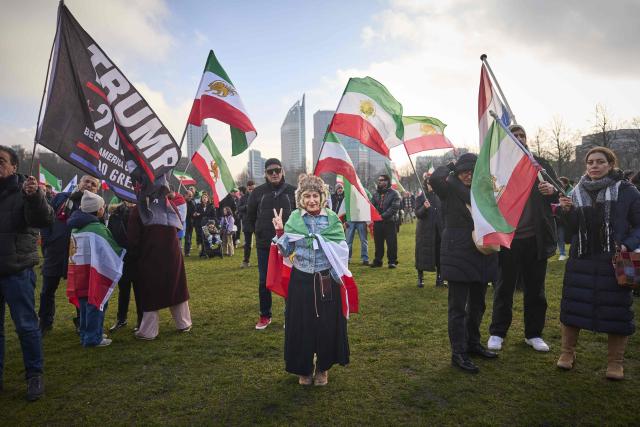A protester flashes the V sign as others wave pre-1979 Islamic Revolution Iranian flags during a demonstration in support of the Iranian people in The Hague on January 31, 2026. (Photo by Phil Nijhuis / various sources / AFP) / Netherlands OUT