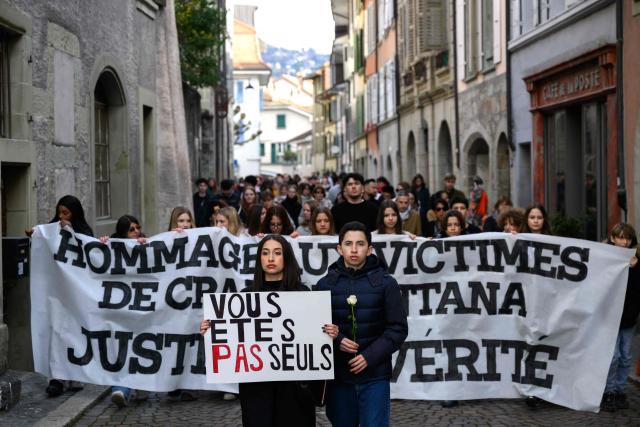 TOPSHOT - An attendee with a placard reading "you are not alone" takes part in a silent march organized in memory of some of the victims of the Crans Montana deadly New Year's Eve fire, in Lutry, near Lausanne, on January 31, 2026. The fire on January 1 at the bar "Le Constellation" left 40 people dead -- including nine French and six Italian nationals -- and injured 116 others, most of them teenagers. (Photo by Harold CUNNINGHAM / AFP)